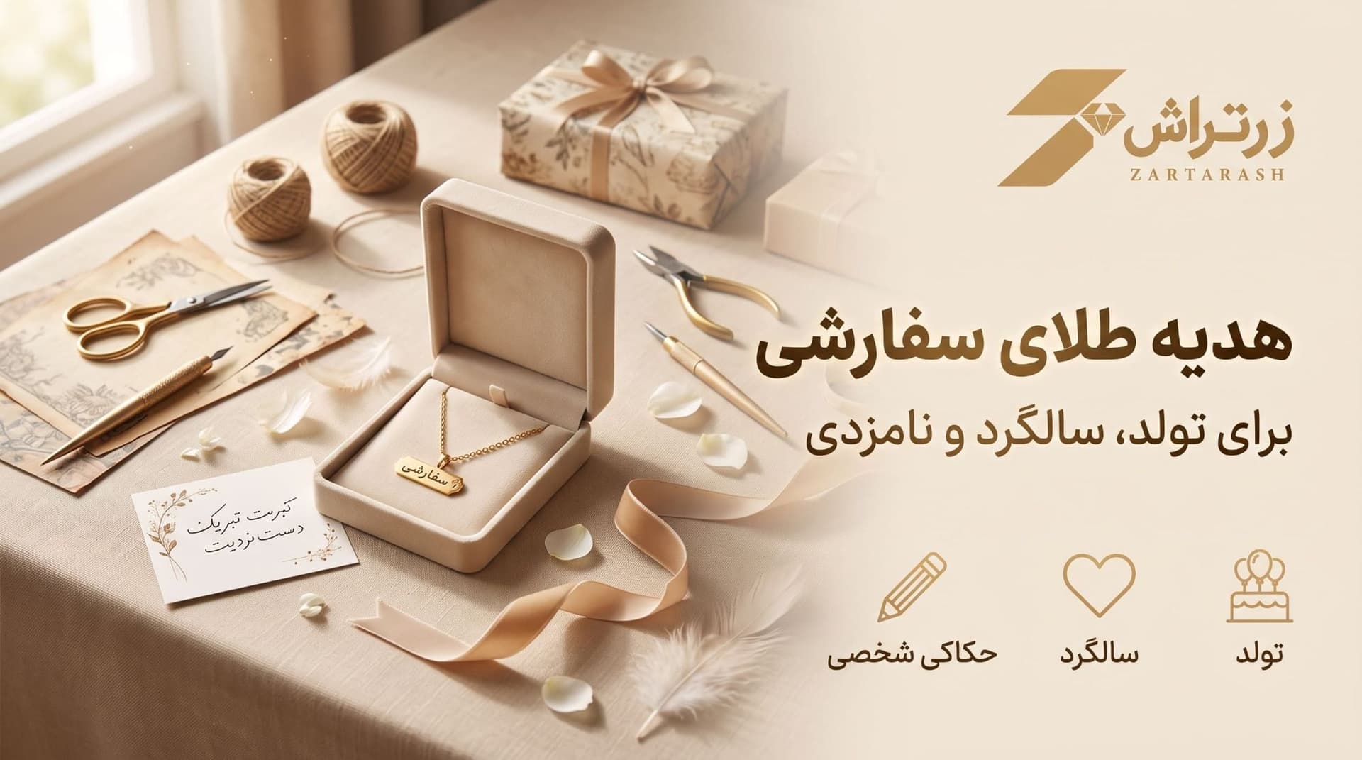 جعبه هدیه باز با آویز طلای حکاکیشده، کارت تبریک و روبان کنار جعبه کادو روی میز